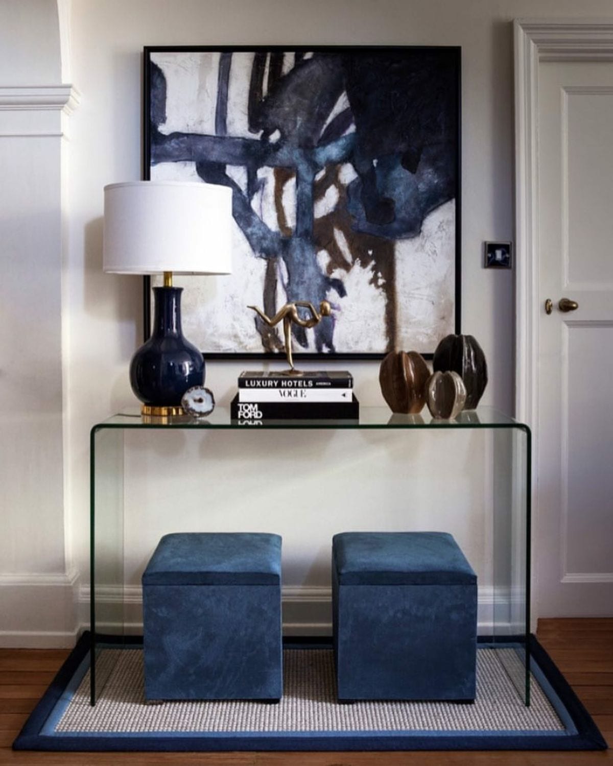 Clear glass console with two navy poufs beneath it