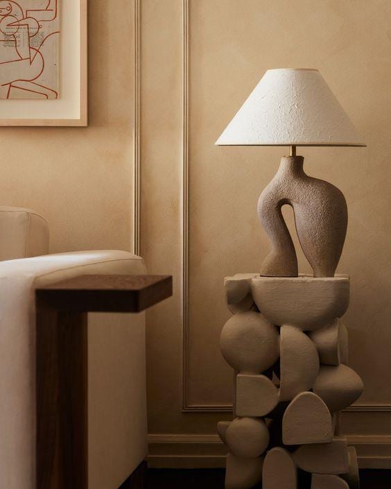 Abstract stone-textured lamp with a linen shade on a sculptural plinth