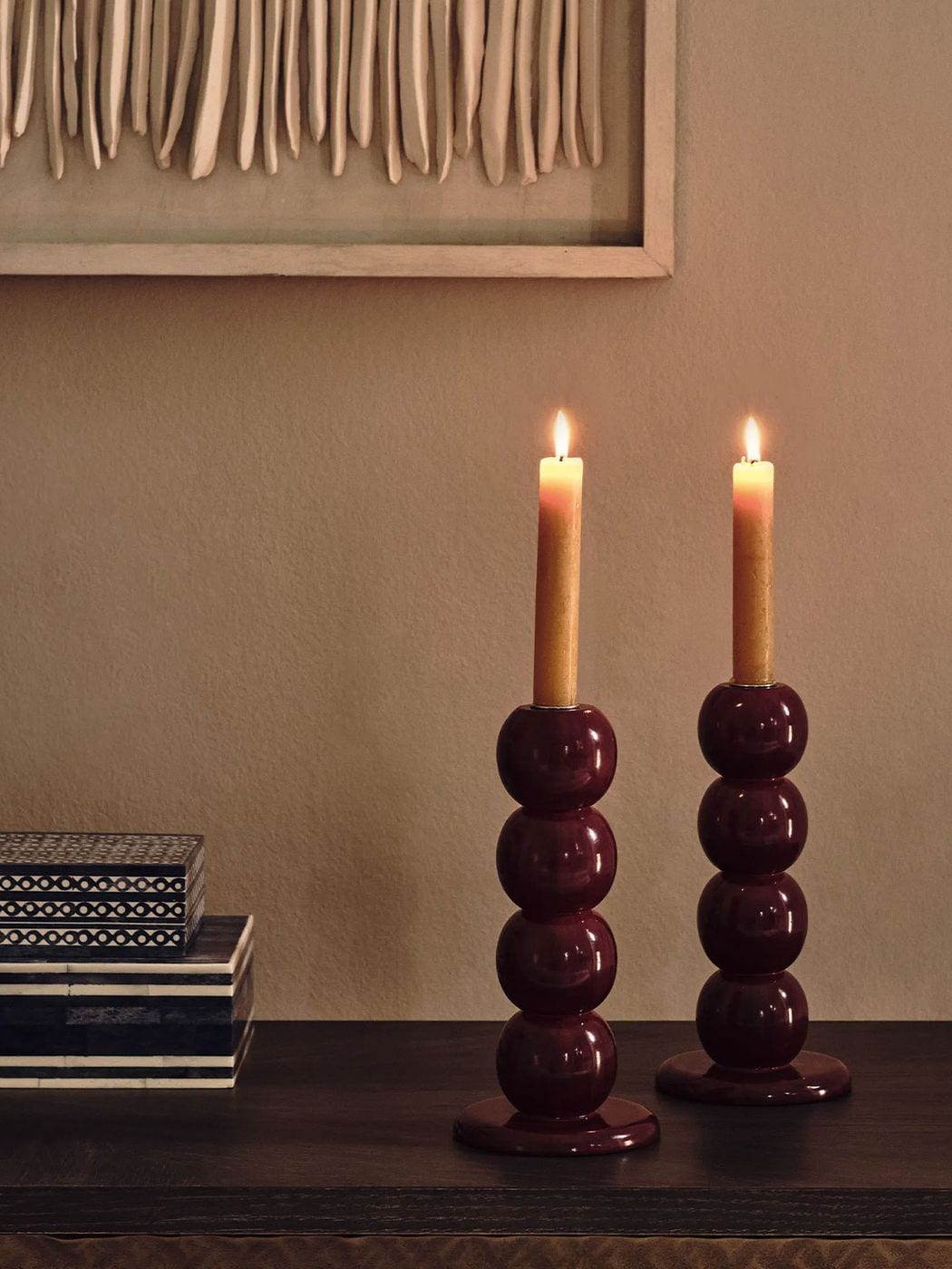 Burgundy stacked-sphere candle holders on a dark sideboard